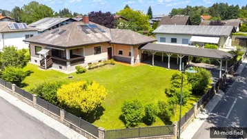 Luftaufnahme eines Einfamilienhauses mit großem Garten, Carport und Solaranlage auf dem Dach.