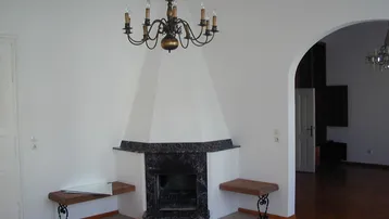 Helles Wohnzimmer mit einem traditionellen Kamin und Parkettboden, ideal für gemütliche Abende.