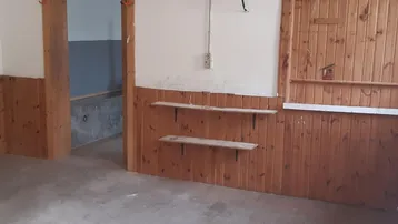 Geräumiger Innenraum mit Holzvertäfelung und Regalen, bereit für individuelle Nutzung oder Lagerung.