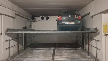 Tiefgarage mit Duplex-Parksystem und geparktem Auto auf der oberen Ebene.