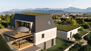 Moderne Villa mit begrüntem Dach, großer Terrasse und Bergblick in grüner Umgebung.