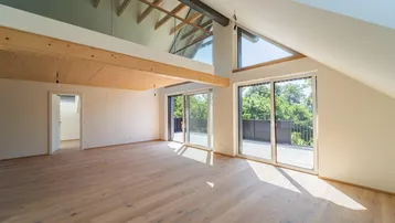 Helles, offenes Wohnzimmer mit Holzboden, hohen Decken und Zugang zu einem Balkon oder einer Terrasse.