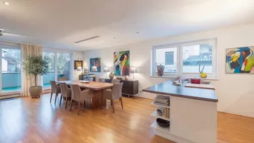 Heller, offener Wohn- und Essbereich mit Holzboden, Zugang zum Balkon und moderner Einrichtung.