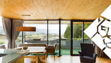 Helles Wohn- und Esszimmer mit Holzboden, großen Fenstern und Bergblick.