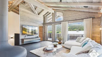 Gemütliches Wohnzimmer im alpinen Stil mit Holzbalkendecke, Kamin und Bergblick.