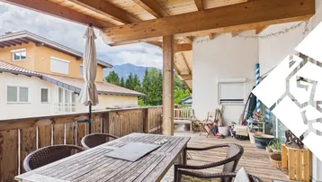 Geräumiger Balkon mit Holztisch, Stühlen und Blick auf die umliegende Berglandschaft.