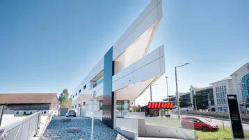 Modernes Geschäftsgebäude mit markanter Architektur und klaren Linien unter blauem Himmel.
