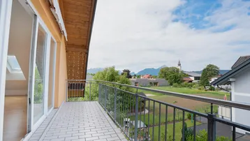 Geräumiger Balkon mit Fliesenboden, Metallgeländer und weitem Blick über die Landschaft und Berge.