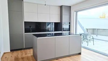 Moderne Küche mit Kücheninsel, integrierten Geräten und direktem Zugang zu einer sonnigen Terrasse.