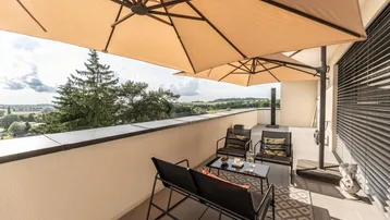 Geräumige Dachterrasse mit bequemen Gartenmöbeln und Sonnenschirmen, ideal für entspannte Stunden im Freien mit Weitblick.