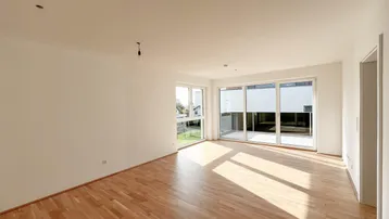 Helles Wohnzimmer mit Parkettboden und Zugang zu einer großen Terrasse.