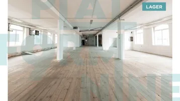 Großer, leerer Lagerraum mit Holzboden, weißen Wänden und sichtbaren Deckeninstallationen, ideal für industrielle Nutzung.