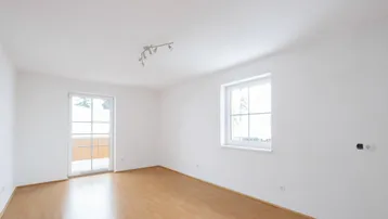 Helles Zimmer mit Laminatboden und Zugang zu einem Balkon oder einer Terrasse, ideal für individuelle Gestaltung.
