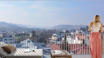 Geräumiger Balkon mit Liegestuhl und weitem Blick über die Stadt und die umliegende Hügellandschaft.