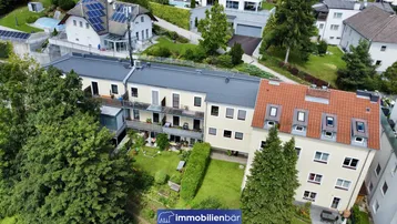 Luftaufnahme eines Wohnkomplexes mit mehreren Gebäuden, umgeben von viel Grün und Bäumen.