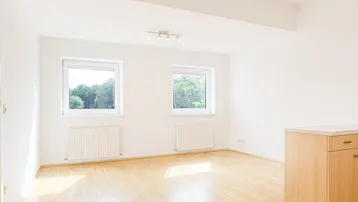 Helles, offenes Wohnzimmer mit Parkettboden und Blick ins Grüne, bereit zur individuellen Gestaltung.