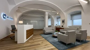 Geräumiger Empfangsbereich mit moderner Rezeption, bequemen Sitzgelegenheiten und gewölbter Decke.