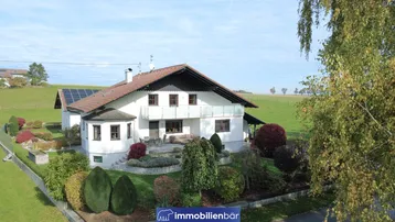 Idyllisches Haus mit gepflegtem Garten, Terrasse und Photovoltaikanlage in ländlicher Umgebung.