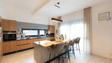 Moderne Einbauküche mit Kücheninsel, Holzfronten und integrierten Geräten, ideal für geselliges Kochen.