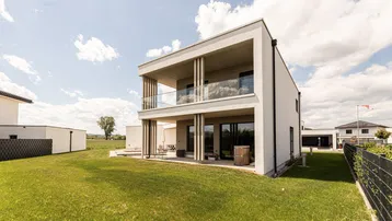 Weitläufiger Gartenbereich hinter dem modernen Wohnhaus mit viel Grün und offenem Horizont.