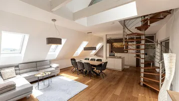Heller, offener Wohn- und Essbereich mit Holzboden, Dachschrägen und einer eleganten Wendeltreppe.