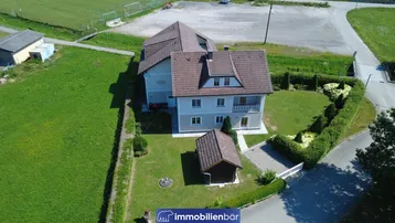 Luftaufnahme eines Einfamilienhauses mit gepflegtem Garten und ländlicher Umgebung.