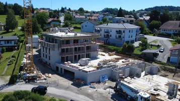 Luftaufnahme einer Neubauwohnung im Bau mit Kran und Blick auf die umliegende Landschaft.
