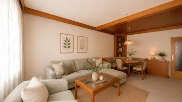 Gemütliches Wohnzimmer mit Ecksofa, Holzbalken und einem Essbereich im Hintergrund.