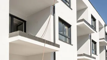 Moderne Fassade eines Neubaus mit Balkonen und großen Fenstern, im Bau.