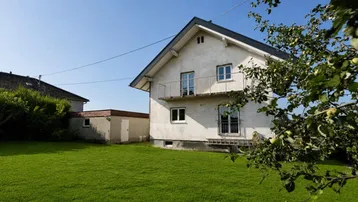 Weißes Einfamilienhaus mit Satteldach, Balkon und großem grünen Garten.