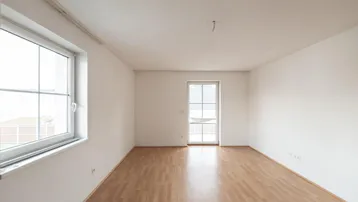 Heller, leerer Raum mit Laminatboden und Zugang zu einem französischen Balkon.