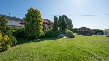 Großer, gepflegter Garten mit Rasenfläche und Blick auf das Einfamilienhaus unter strahlendem Sonnenschein.