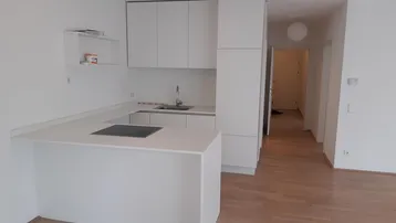 Moderne, offene Küche mit weißen Schränken, Kochinsel und hellem Holzfußboden in einem Wohnbereich.