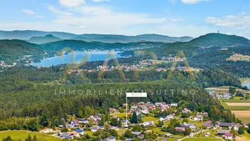 Luftaufnahme eines Dorfes mit See und Bergen im Hintergrund, die Immobilie ist markiert.