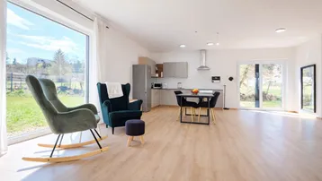 Heller offener Wohn- und Essbereich mit integrierter Küchenzeile und großen Fenstern zum Garten.
