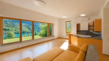 Heller Wohn- und Essbereich mit großen Fenstern, Seeblick und integrierter Küchenzeile.
