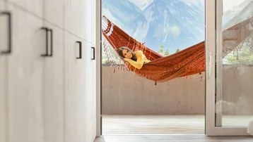 Heller Innenraum mit Zugang zu einem Balkon und beeindruckendem Bergblick.