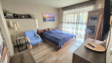 Gemütliches Schlafzimmer mit Holzboden, großem Bett und Zugang zu einem Balkon oder einer Terrasse.