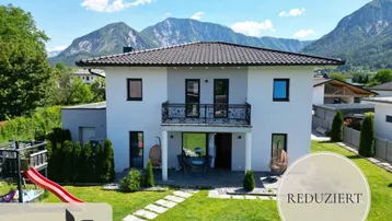 Modernes Einfamilienhaus mit gepflegtem Garten, Spielplatz, Terrasse und beeindruckendem Bergblick.