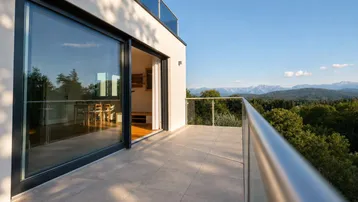 Geräumiger Balkon mit Fliesenboden und Glasgeländer, bietet einen weiten Blick auf die Berge und die Landschaft.