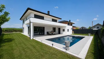 Modernes Einfamilienhaus mit großem Garten, privatem Pool und überdachter Terrasse.