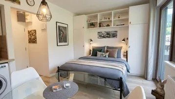 Helles Studio-Apartment mit Schlafbereich, kleinem Essplatz und Zugang zum Balkon.