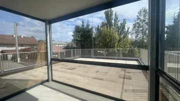 Verglaste Loggia mit Blick auf die Umgebung und angrenzender offener Terrasse.