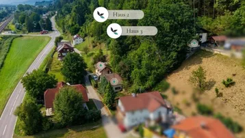 Luftaufnahme eines Wohngebiets am Waldrand mit markierten Häusern und umliegender Natur.