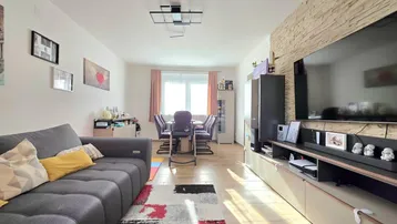 Helles Wohn- und Esszimmer mit modernem Sofa, Esstisch und dekorativer Steinwand.