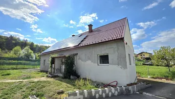 Einfamilienhaus mit Solaranlage auf dem Dach und sonnigem Grundstück, teilweise renovierungsbedürftig.