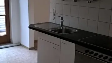 Helle Küche mit weißen Schränken, Spüle und Kochfeld, bereit für die Installation weiterer Geräte.