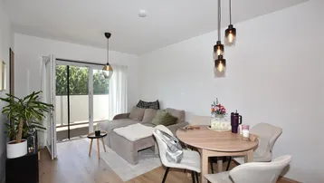 Helles Wohn- und Esszimmer mit Holzboden, Zugang zum Balkon und moderner Beleuchtung.