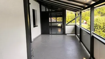 Geräumiger überdachter Balkon mit Blick ins Grüne, ideal für entspannte Stunden im Freien.