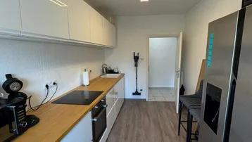 Moderne Küche mit weißen Schränken, Holz-Arbeitsplatte und integrierten Geräten.